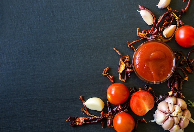 Salsa di pomodoro con aglio e pepe secco su ardesia scura, vista dall'alto