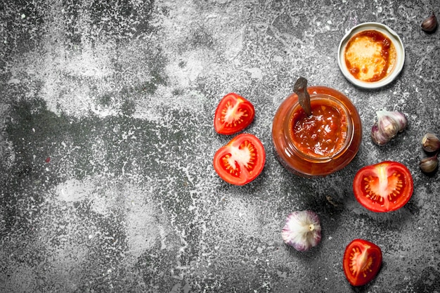 Tomato sauce with garlic and herbs in a glass jar on rustic table