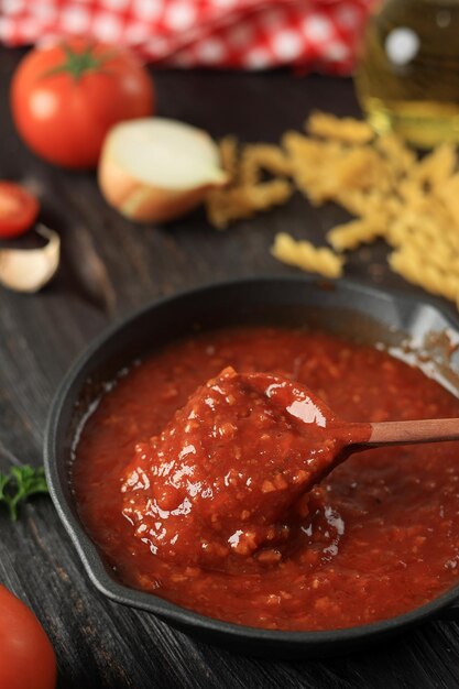 Foto salsa di pomodoro con cucchiaio di legno in padella di ghisa