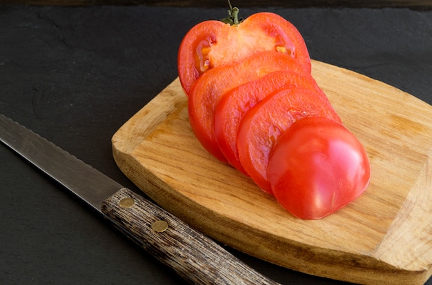 Tomato sliced on a wooden Board. black background