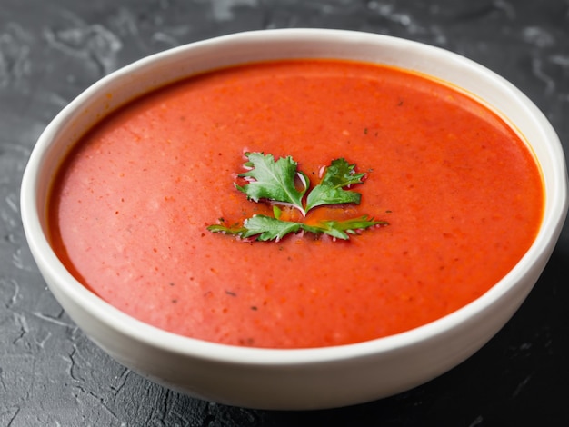 Tomato soup in ceramic bowl on Dark background