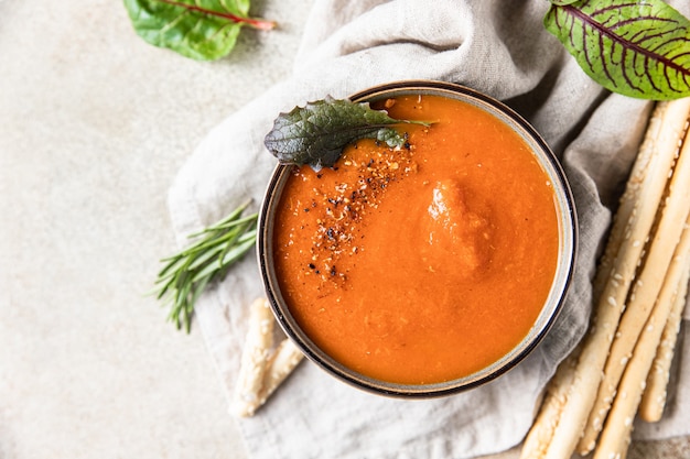 Tomato soup garnish with ground pepper rosemary and bread sticks