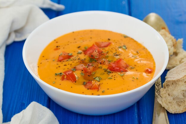 Tomato soup in white bowl on wooden surface