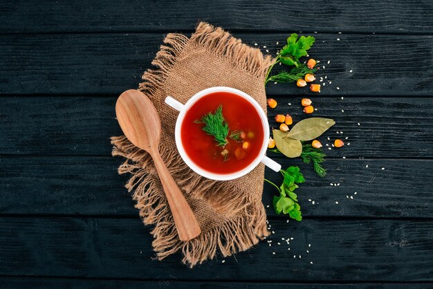 Zuppa di pomodoro con peperoncino e verdure cibo sano su uno sfondo di legno nero vista dall'alto copia spazio per il testo