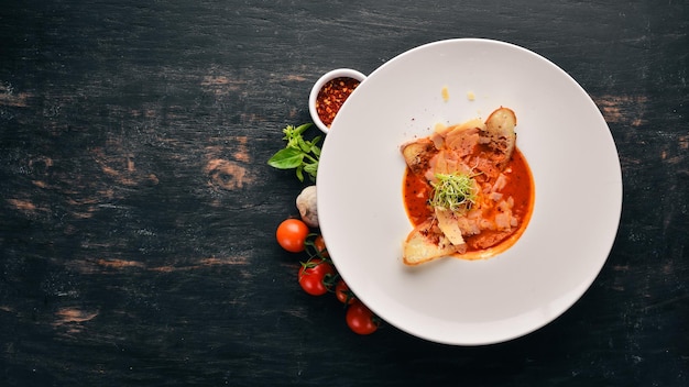 Tomato soup with Parmesan cheese and croutons of bread. Top view. Free space for your text. On a wooden background.