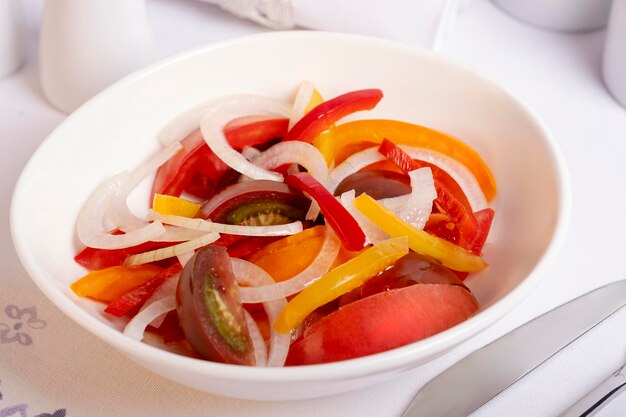 tomato and sweet pepper salad in a white bowl on the table
