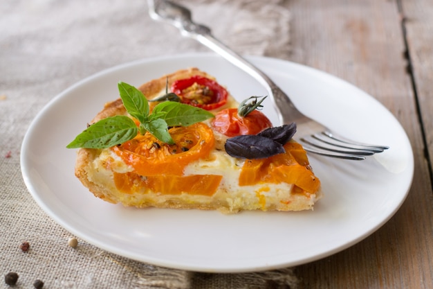 Tomato tart made with shortcrust  pastry, red and yellow tomatoes, cheese and cream. Concept of healthy eating or vegetarian food on rustic wooden background