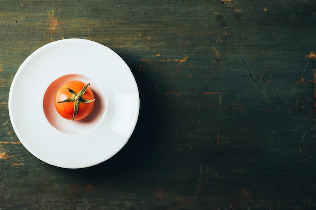 A tomato on a white plate top view