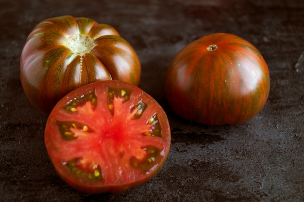 Tomato whole and sliced on a black background.