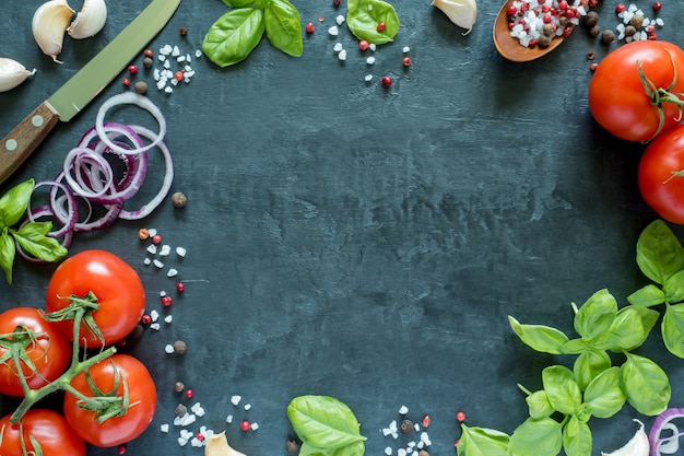 Photo tomatoes basil garlic and spices on a stone table. the concept of cooking. top view with space for text