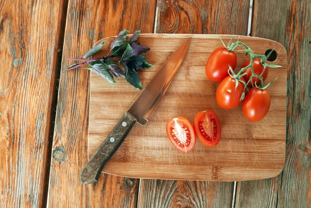 Tomatoes basil and a knife lie on a cutting board