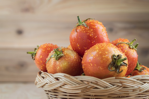 Photo tomatoes in basket on wooden table