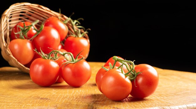 Tomatoes, beautiful tomatoes falling from a straw basket on rustic wood, selective focus.