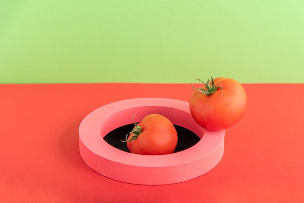 Tomatoes come out from the hole through a pink ring on a green and red background