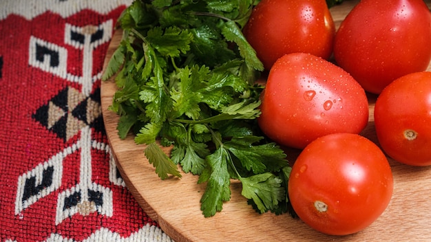 Pomodori, cetrioli ed erbe aromatiche su un tagliere.