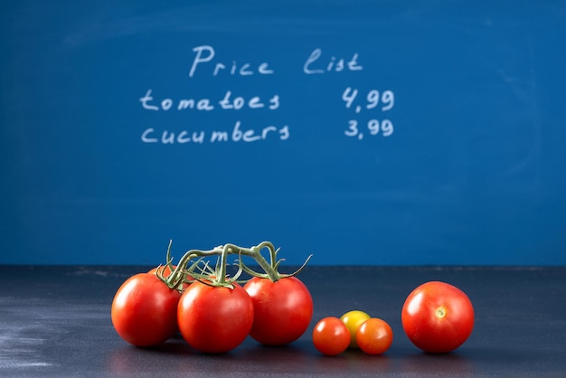 Tomatoes on dark blue background with price list.