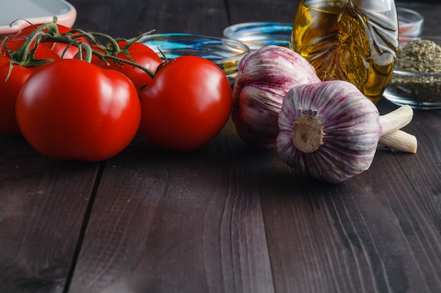 Tomatoes and garlic on wooden black table  surface