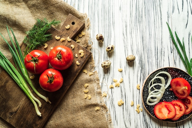 Pomodori, cipolle verdi, aneto, uova di quaglia su una lavagna 3