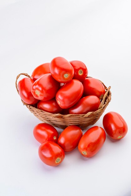 Tomatoes inside straw basket isolated on white background