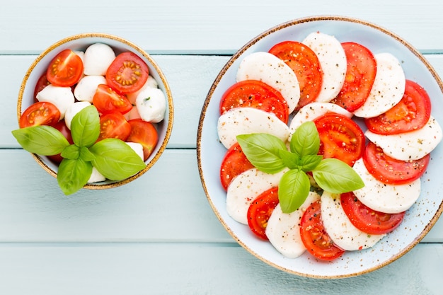 Tomatoes, mozzarella cheese, basil and spices on gray slate stone chalkboard. Italian traditional caprese salad ingredients. Mediterranean food.