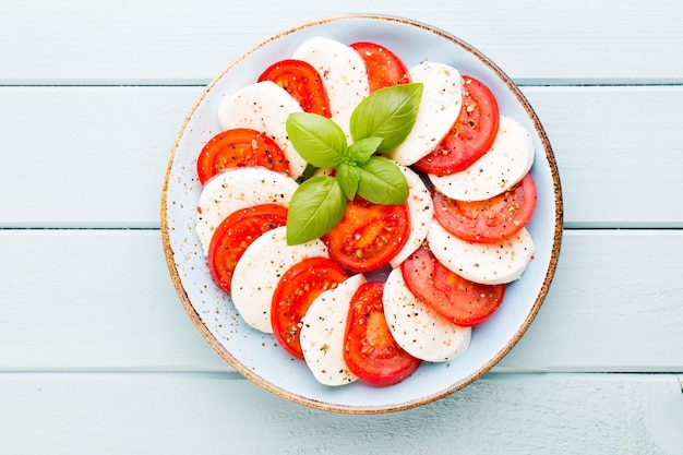 Tomatoes mozzarella cheese basil and spices on gray slate stone chalkboard Italian traditional caprese salad ingredients Mediterranean food