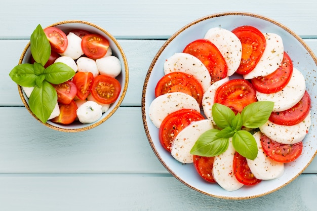 Tomatoes, mozzarella cheese, basil and spices on gray slate stone chalkboard. Italian traditional caprese salad ingredients. Mediterranean food.