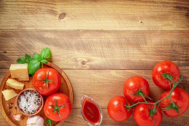 Tomatoes parmesan cheese and spices on wooden background Top view copy space