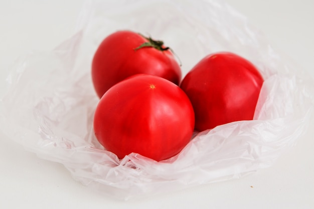  tomatoes in a plastic bag on a light background