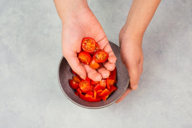 ボウルにトマトと赤ピーマンのスライスを入れ、パプリカ野菜を使った健康的な食べ物を準備します