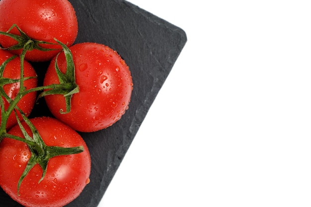 Tomatoes on a slate cutting board isolated white background