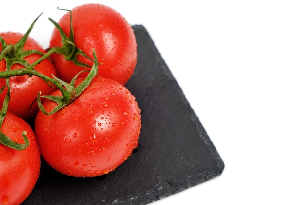 Tomatoes on a slate cutting board isolated white background