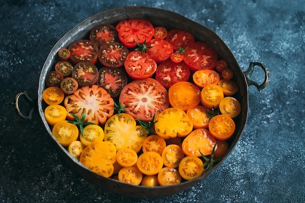 Foto i pomodori a fette di diversi colori vengono visualizzati come una sfumatura su uno sfondo scuro.