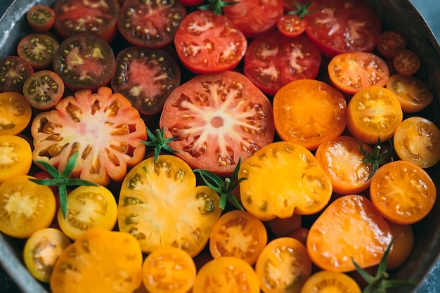Foto i pomodori a fette di diversi colori vengono visualizzati come una sfumatura su uno sfondo scuro.