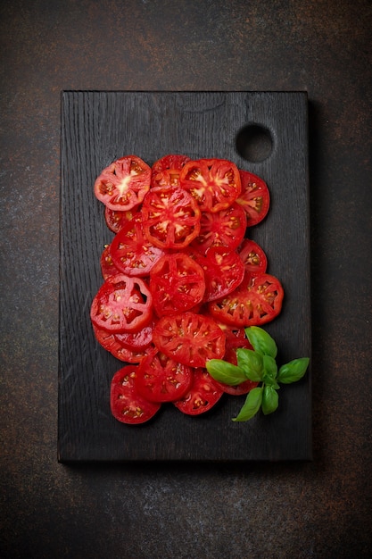 Tomatoes slices with basil leaves and pepper