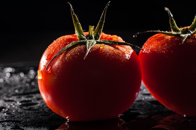 Tomatoes with drops of water on black background