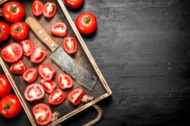 Tomatoes with old hatchet on the tray on black chalkboard