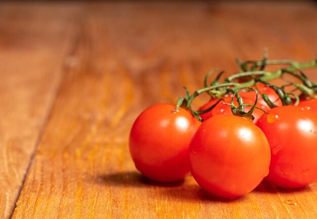 Tomatoes on a wooden table with a vine on the vine