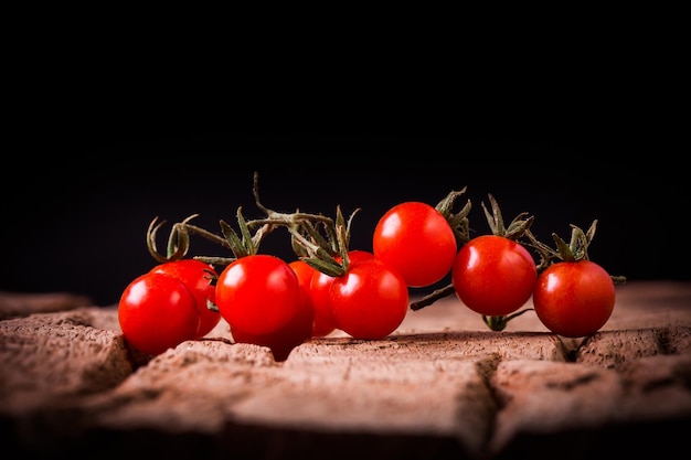 Tomatos in wooden plate on black background
