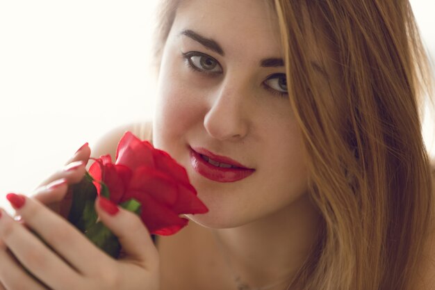 Foto ritratto tonico del primo piano della giovane donna che tiene la rosa rossa