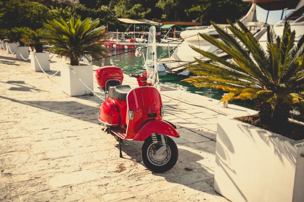 Toned photo of retro red scooter parked at sea port