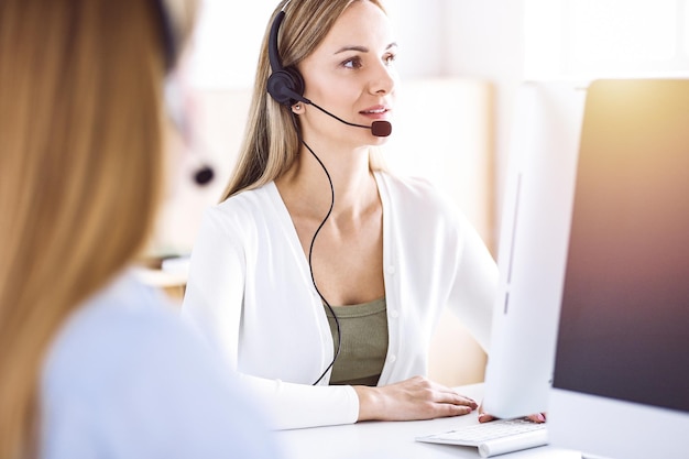 Toned portrait of call center operator at work. Group of people in a headset ready to help customers. Business concept.