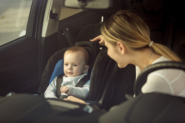 Toned portrait of mother and baby boy sitting in car on front seats