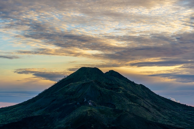 Toneelzonsopgang bij Batur en Agung-vulkaan, Kintamani, eiland Bali, Indonesië. Sunrise vulkaan uitzicht vanaf de top van de berg Batur, natuurlandschap. Bewolkt landschap met silhoutte van vulkanische bergen