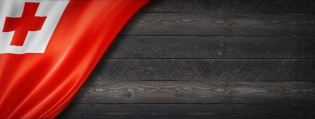 Tonga flag on black wood wall. Horizontal panoramic banner.