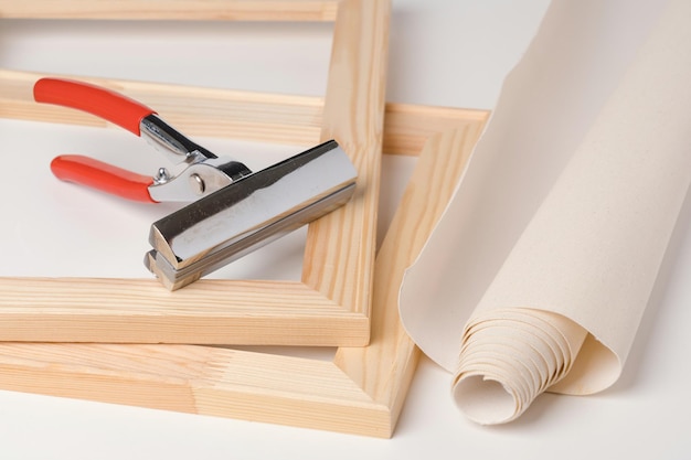 Tongs, canvas and wooden stretchers for stretching canvas on a\
white background