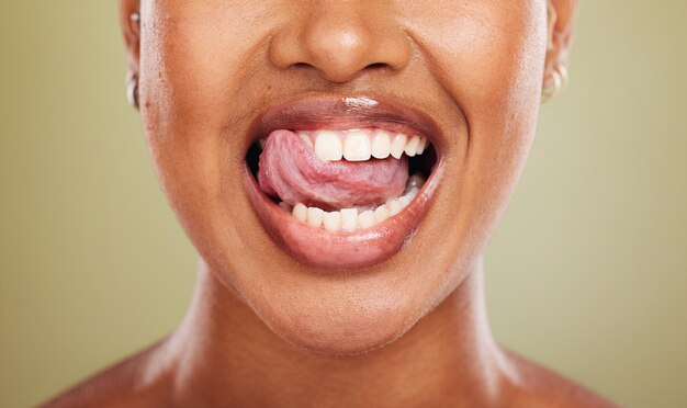 Foto tongtanden en afrikaanse vrouw in close-up met likglimlach of blij voor tandheelkundig welzijn in studio model mond of perfect tanden bleken voor medische gezondheid of schoonheid door achtergrond in de gezondheidszorg