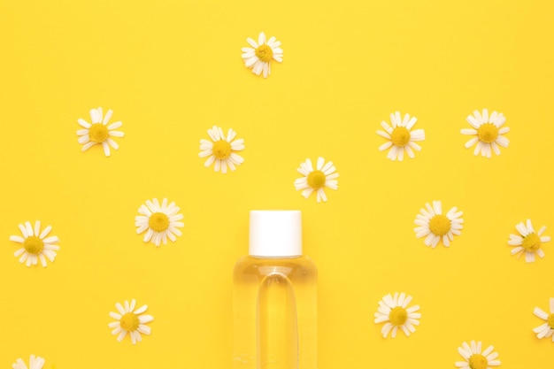 Tonic water met bloemenextracten voor huidverzorging Natuur cosmetica in glazen fles met pipet en kamille bloemen op gele achtergrond Gezichts- en lichaamsverzorging spa concept