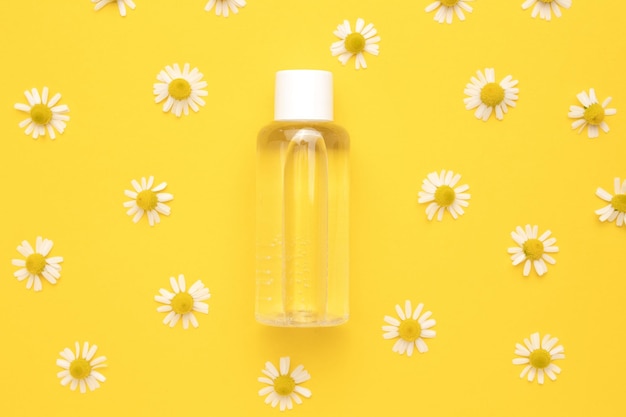 Tonic water met bloemenextracten voor huidverzorging Natuur cosmetica in glazen fles met pipet en kamille bloemen op gele achtergrond Gezichts- en lichaamsverzorging spa concept