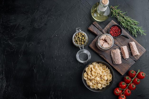 Tonijnpasta-ingrediënten, op zwarte achtergrond, bovenaanzicht met kopieerruimte voor tekst