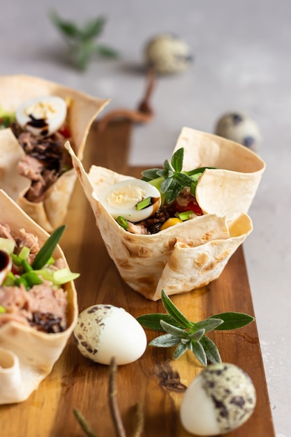 Tonijnsalade met komkommer, paprika, maïs en kwartel ei in taartjes gemaakt van lavash